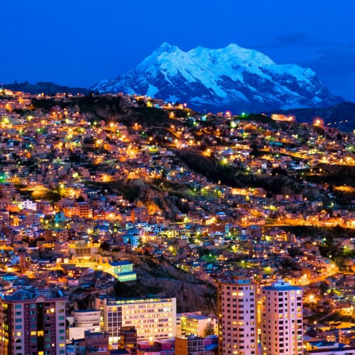 Fotografía añerea de la ciudad de la paz en Bolivia anocheciendo con montañas al fondo