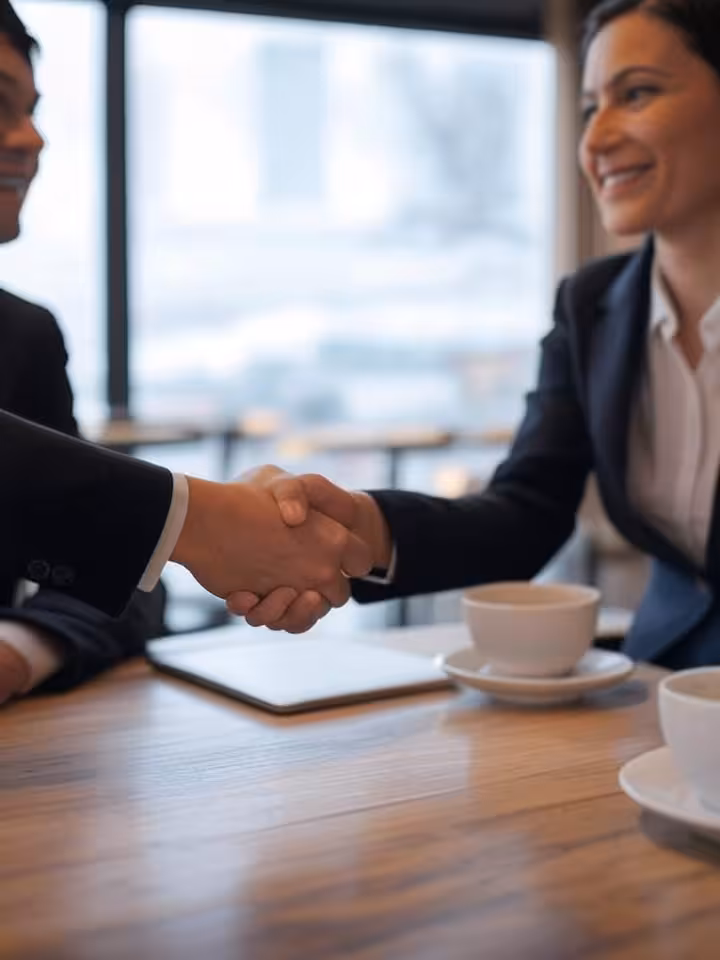 Two people shaking hands across a café table, symbol of mutual agreement, selective focus, professio